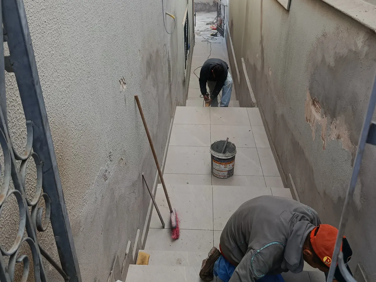 Profissional assentando revestimento em corredor lateral
